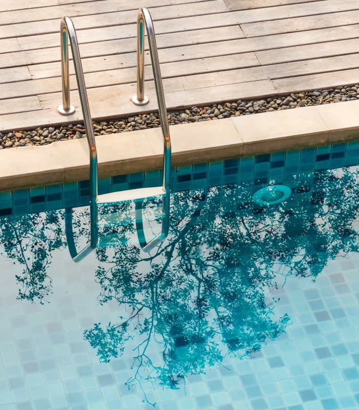 Échelle en inox au bord d’une piscine avec plage en bois