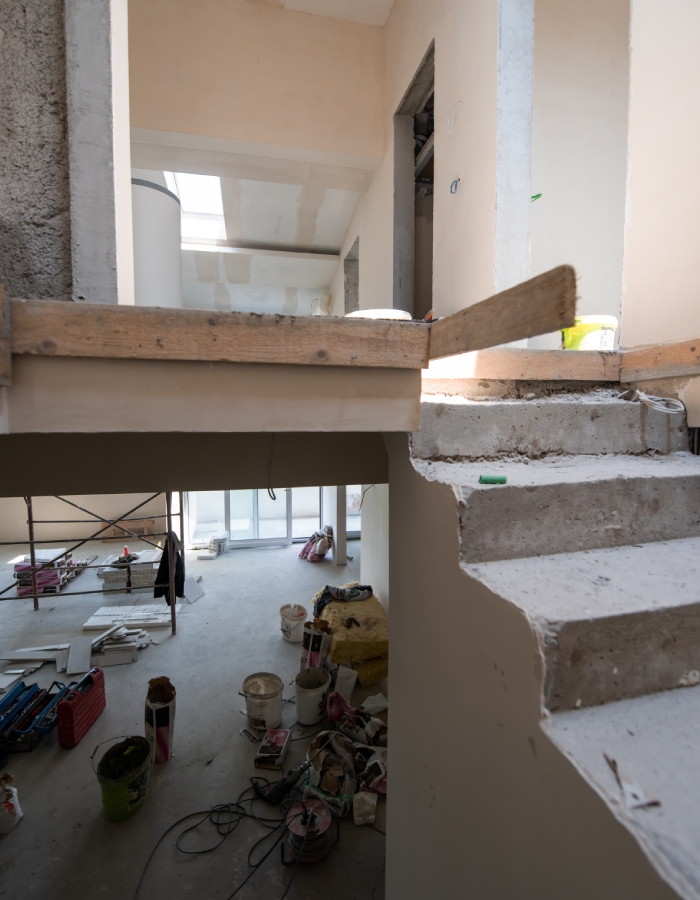 Intérieur de maison en rénovation avec escalier brut et chantier en cours