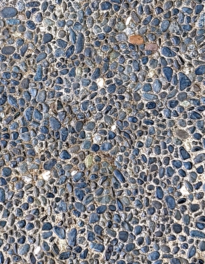 Surface en béton désactivé avec galets bleus apparents